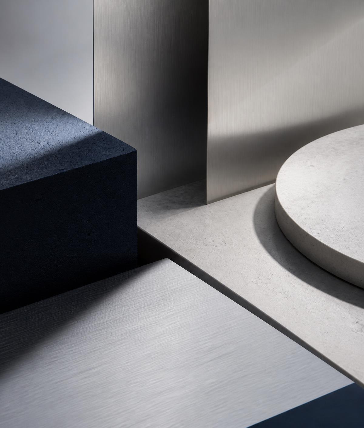 Navy stone, pale limestone and brushed aluminium planes in a minimal composition